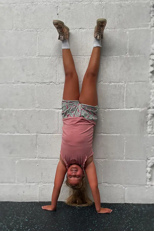 ART CrossFit Kidsles waarbij meisje een handstand doet.